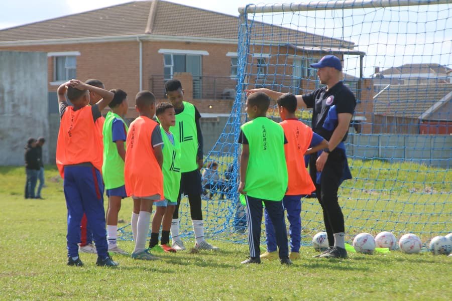 A coach briefs a group of young Shosholoza players in front of the goal